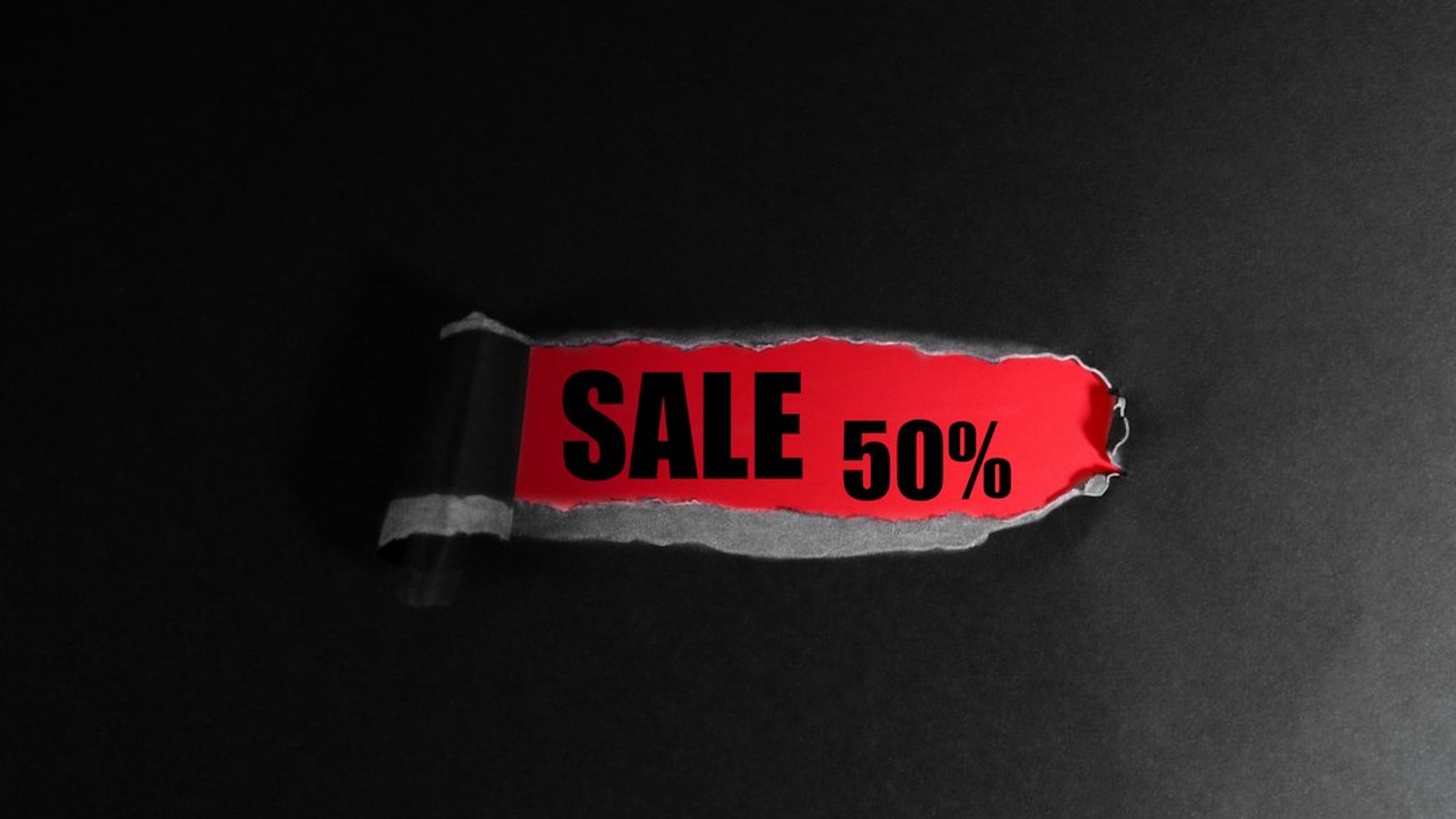 A red price tag reading "sale 50%" hanging against a black background