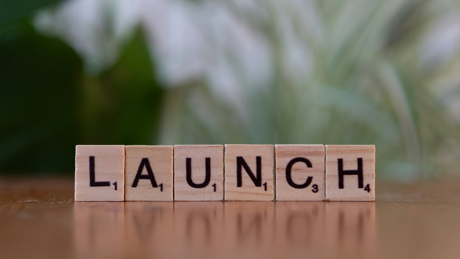 Wooden tile blocks arranged to spell the word "launch" on a plain surface