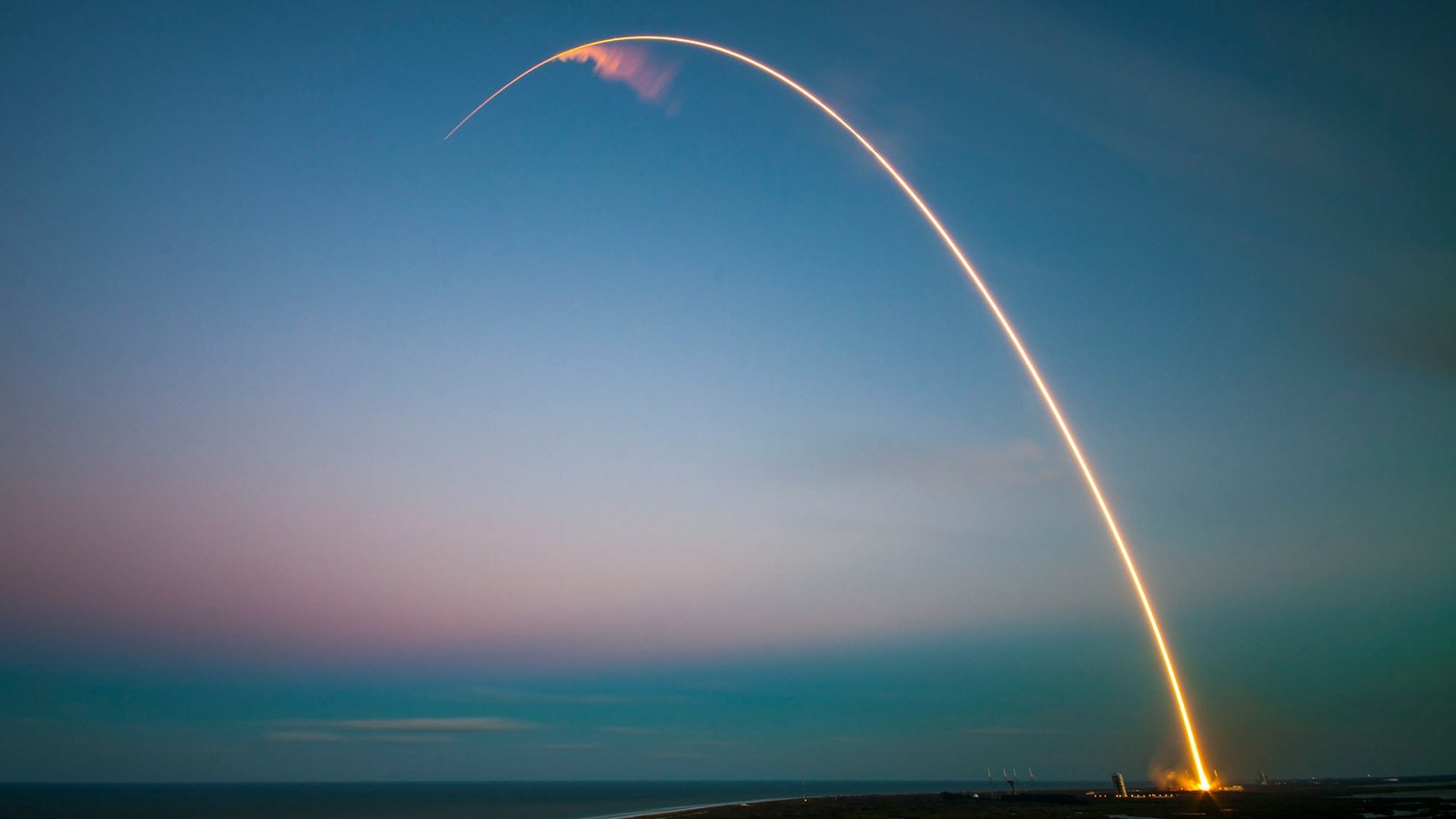 A rocket leaving a bright light trail against a dusk sky