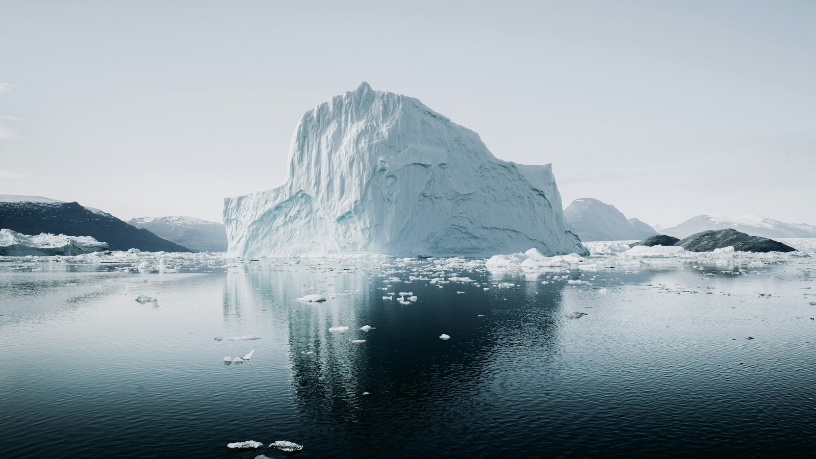 An arctic iceberg reflected in still dark water, with most of its mass below the surface