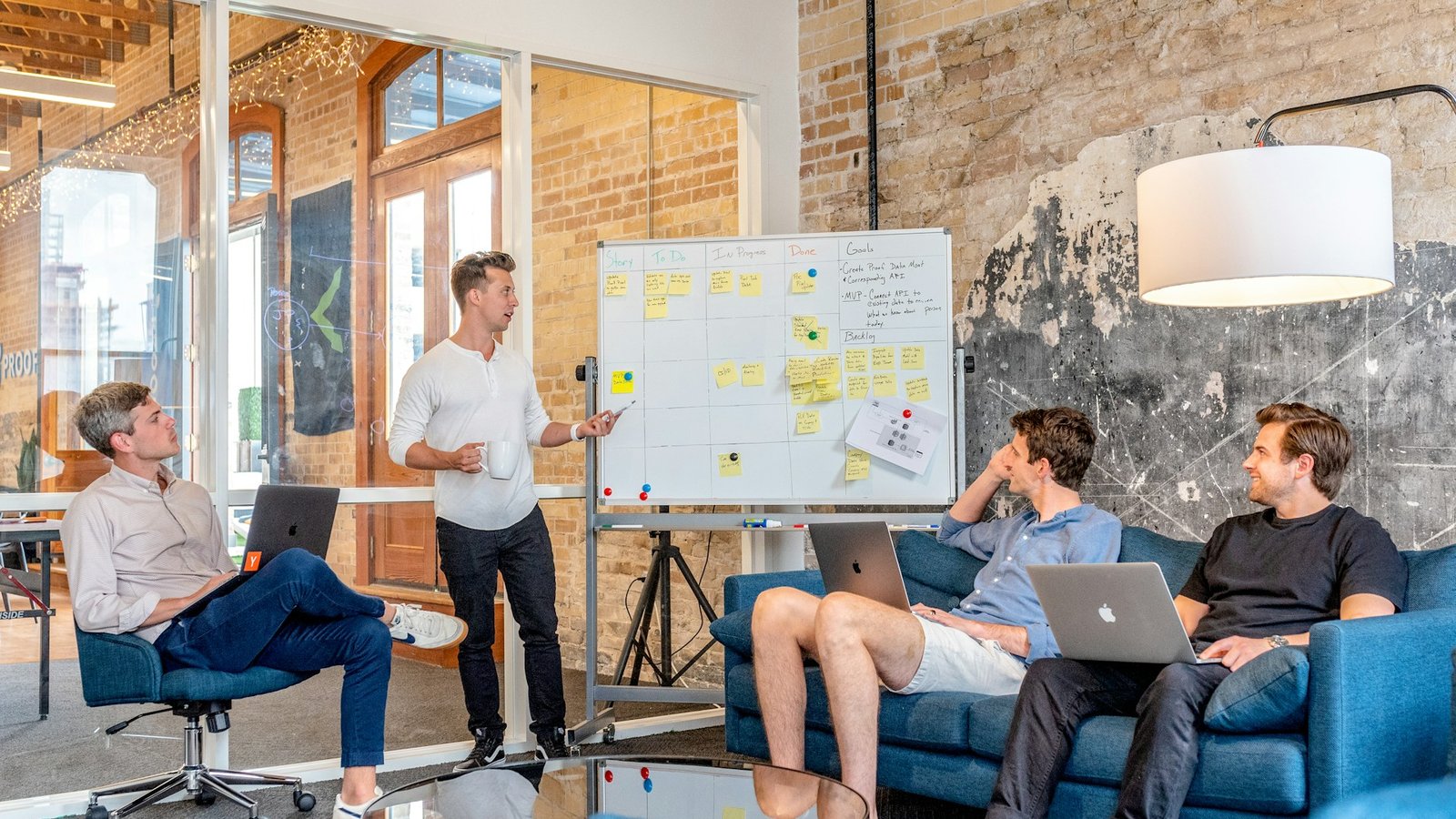 A founder at a whiteboard leading a working session with three people on laptops