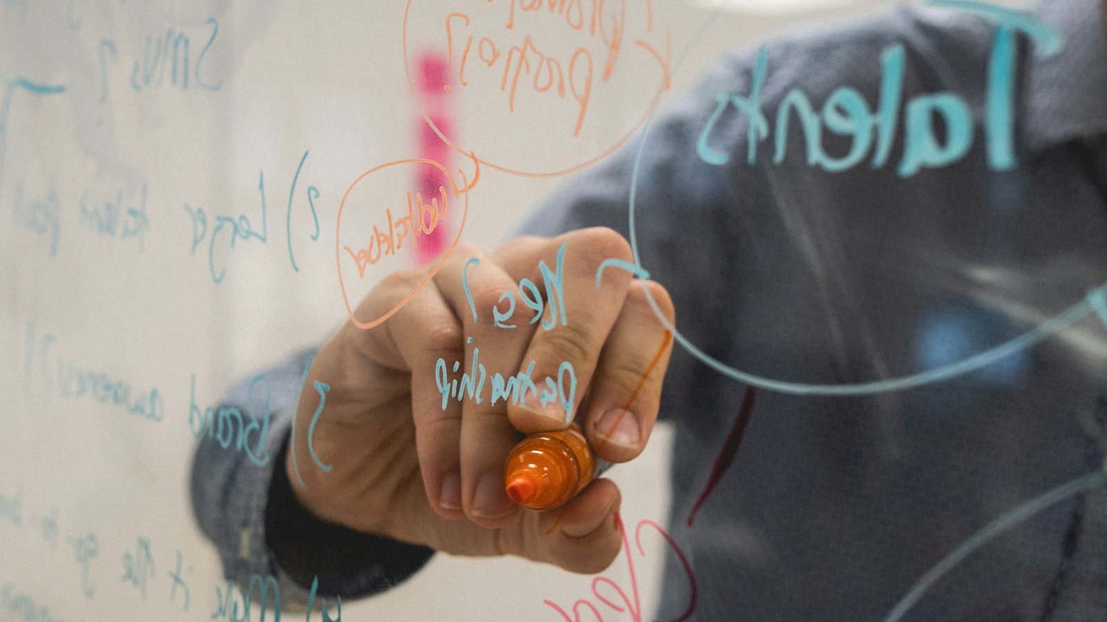 A founder sketching pricing options and arrows on a glass whiteboard