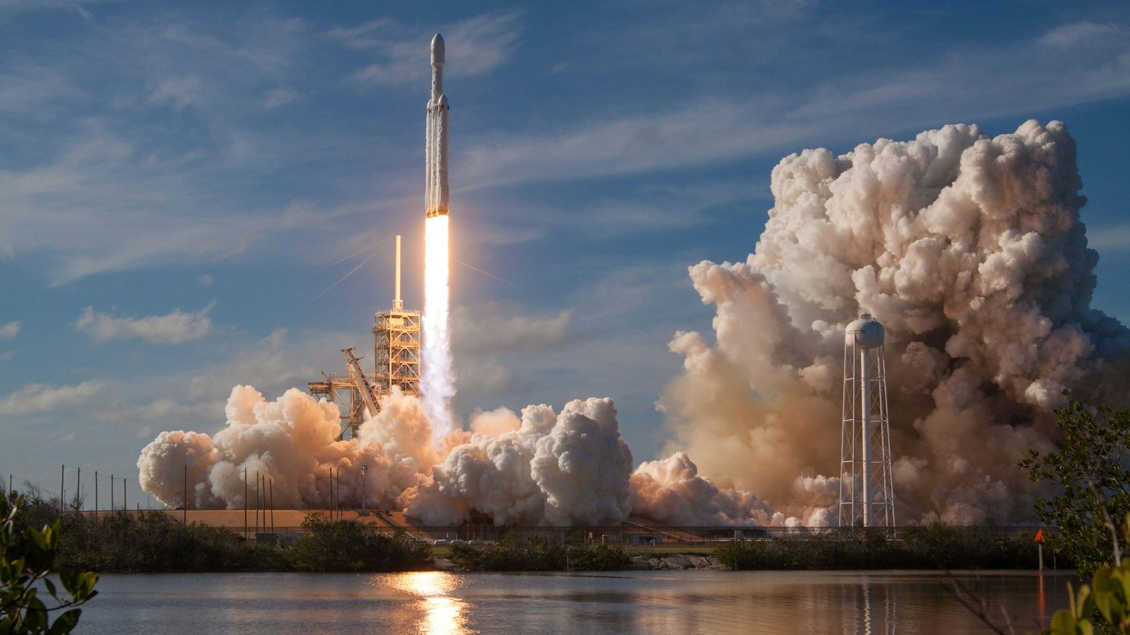 Long-exposure photo of a rocket launching at dusk, smoke trail curving up into the sky