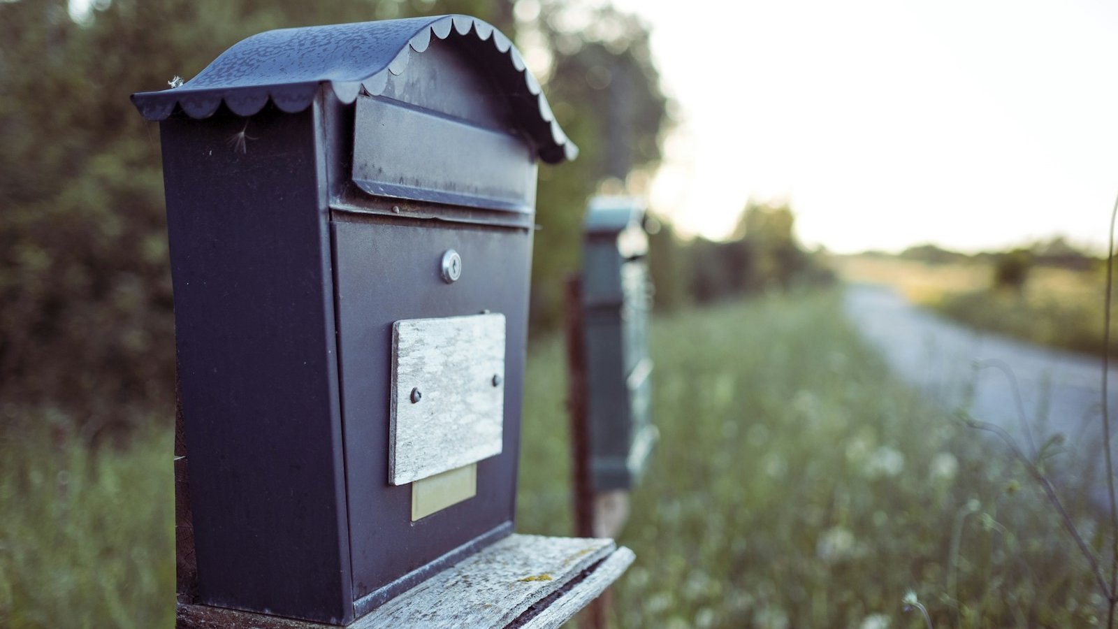 A black mailbox standing outdoors against a plain background