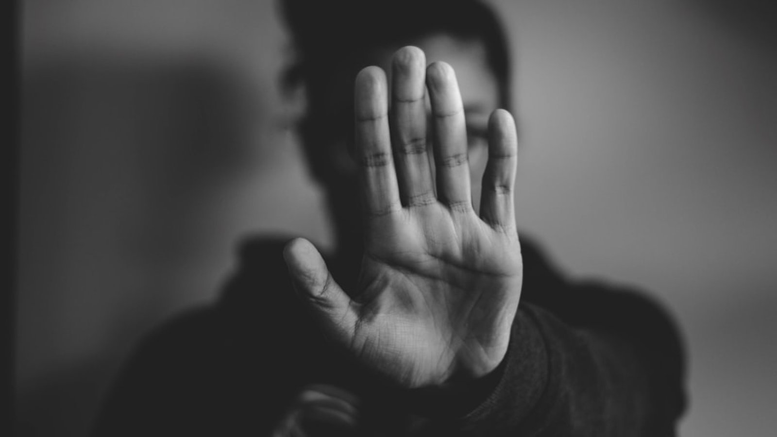 Close-up of a person holding both hands up in a stop gesture