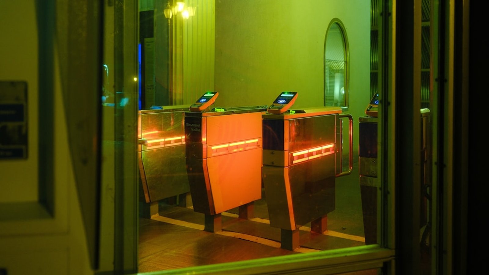 Entrance turnstiles in a station, illuminated with orange and green lights