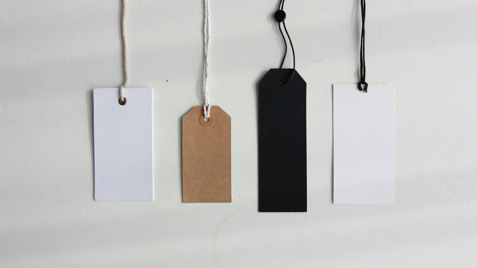 Four handwritten paper price tags tied with string